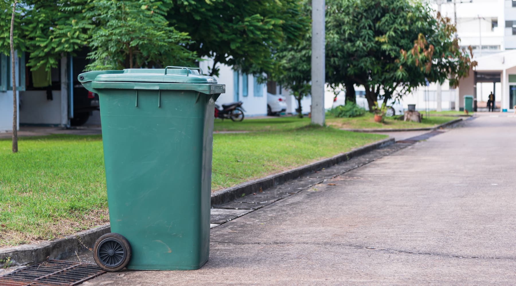 Green big size wheelie bin in a street. Garbage container ready